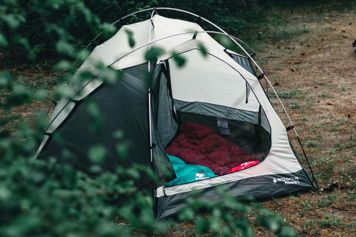 Camping tent and sleeping bags in forest — equipment that requires moisture-protected seasonal storage