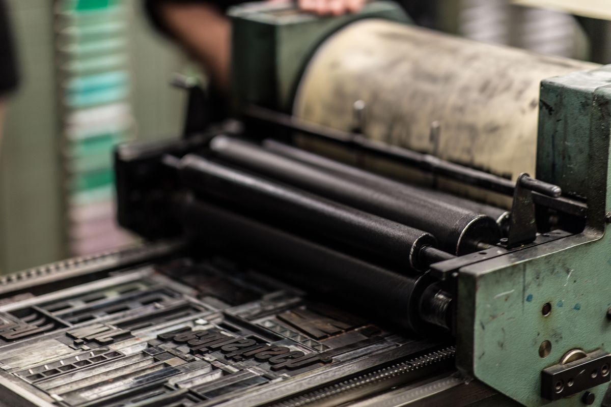 Vintage printing press with colorful ink cans in workshop