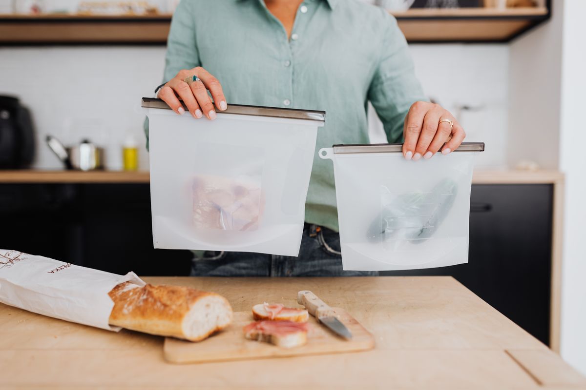 Woman holding reusable food storage bags in kitchen for vacuum sealing and sous vide