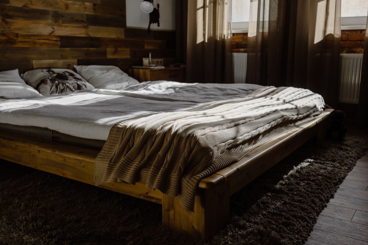 Wooden bed frame with mattress and blanket in bedroom for jumbo bedding vacuum storage