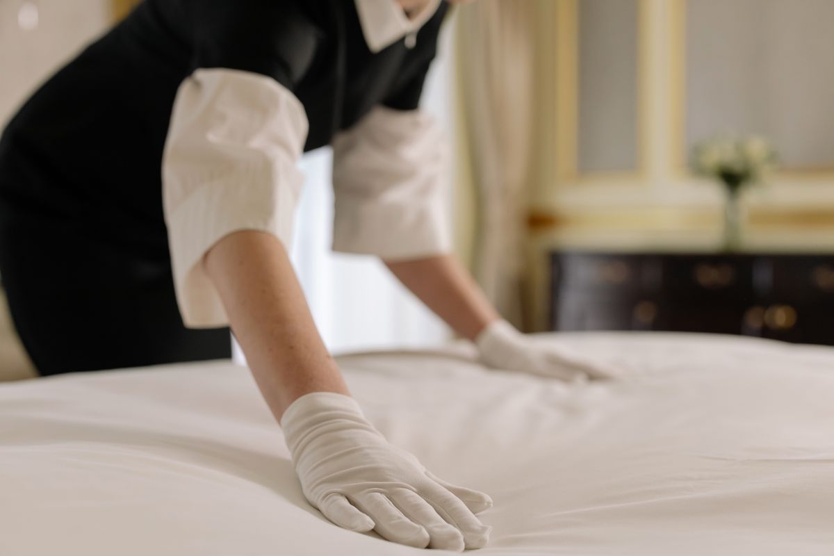 Hotel housekeeper fixing bed linen in luxurious hotel room for hospitality storage solutions