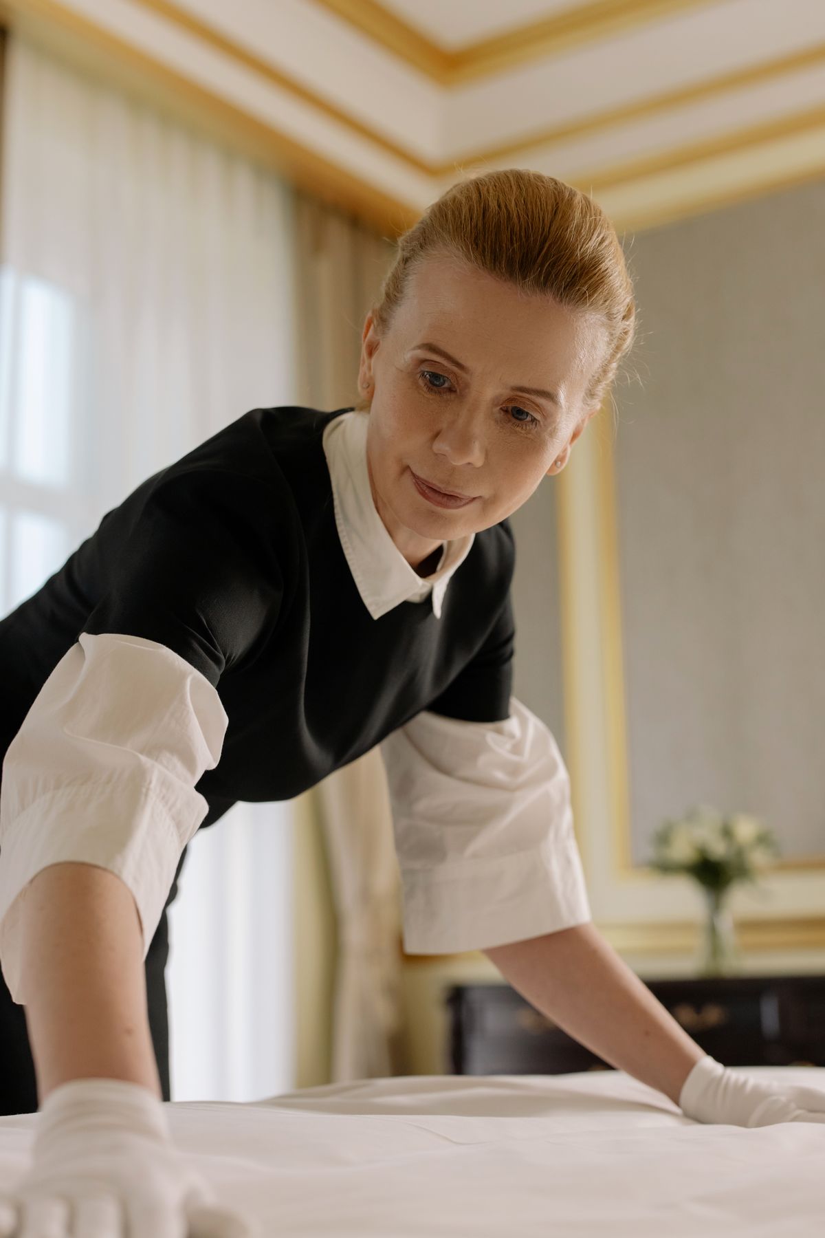 Housekeeper arranging bed linen in hotel room for hospitality industry vacuum storage