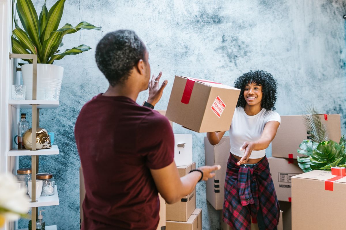 Friends joyfully unpacking moving boxes in new home