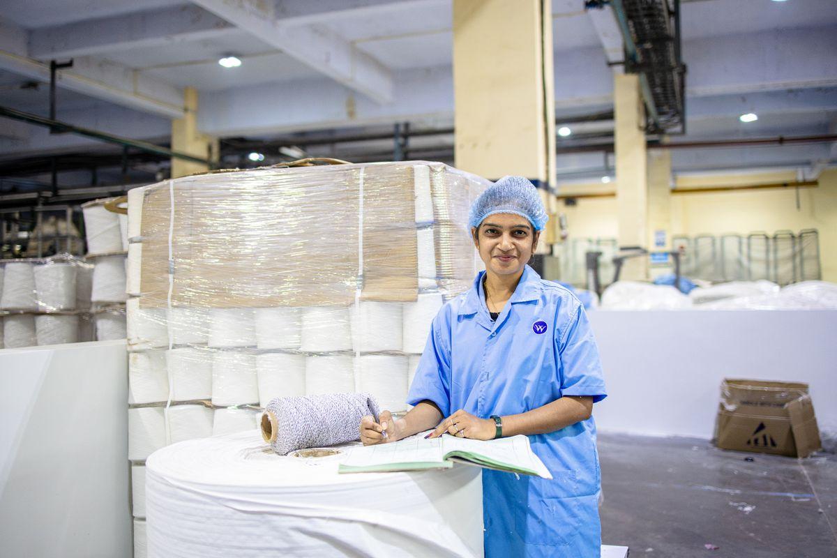 Factory worker inspecting textile rolls representing quality evaluation of vacuum bag samples